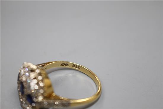 A Victorian style 18ct, three stone sapphire and six stone diamond set circular cluster ring, with diamond set shoulders,